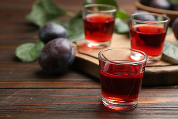 Delicious plum liquor on wooden table. Homemade strong alcoholic beverage
