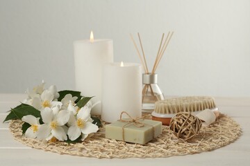 Fototapeta na wymiar Composition with beautiful jasmine flowers, soap and burning candles on white wooden table