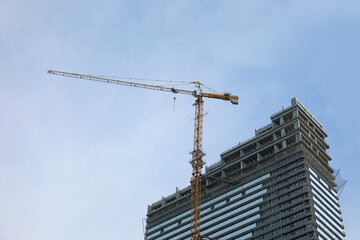 Fototapeta na wymiar Construction site with tower crane near unfinished building, low angle view