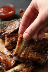 Woman with tasty grilled ribs at table, closeup