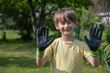 Boy in home garden wearing gardening gloves