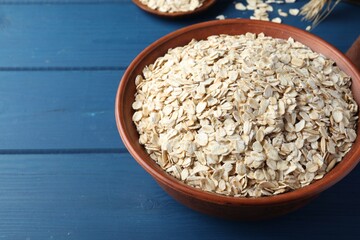 Bowl of oatmeal on blue wooden table, space for text