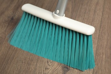 Sweeping wooden floor with plastic broom, closeup