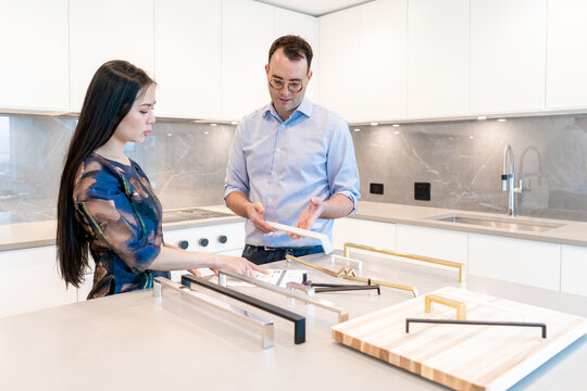 Male and female viewing and discussing kitchen cabinet handles to make a selection for their home interior decor.