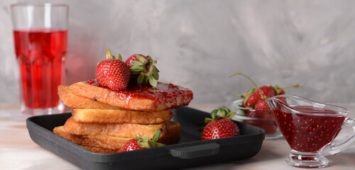 Frying pan with tasty French toasts and strawberry jam on grunge background