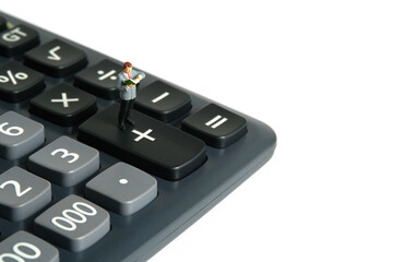 Miniature people toy figure photography. A men student standing above calculator, isolated on white background