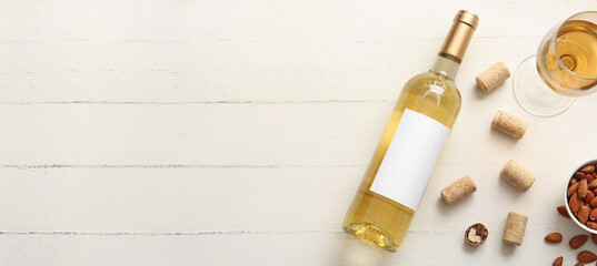 Bottle of white wine with corks on light wooden background with space for text