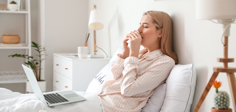 Sick young woman with laptop at home