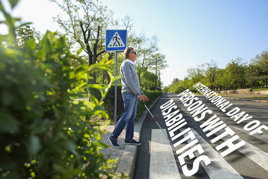 Blind senior man crossing road in city. International Day of Persons with Disabilities - Powered by Adobe