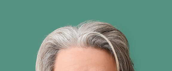 Senior man with grey hair on green background, closeup