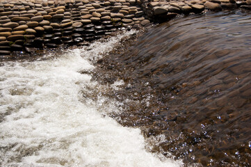 Water streams of an artificial stream among pebbles