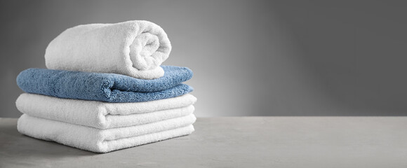 Clean soft towels on table against grey background with space for text