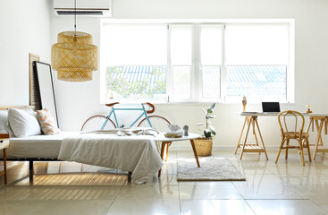 Interior of light bedroom with bicycle and workplace