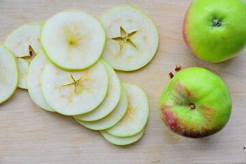 Heap of cutting into thin slices apples for cooking and preparing on wooden board next pair apple. Top view, flat lay