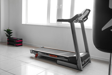 Modern treadmill near window in gym