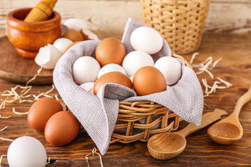 Wicker basket with fresh chicken eggs on wooden table