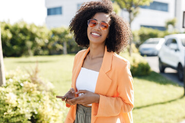 smiling Afro American woman with phone outdoors