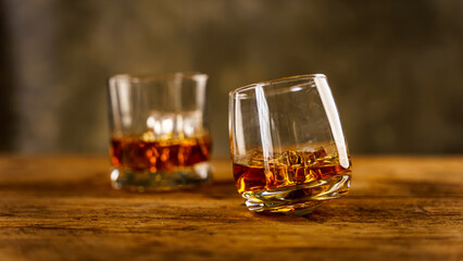 Wiskey in a glass with the ice cubes on the reflective black surface. Bar drinking menu