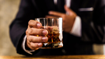 Closeup of executive holding whiskey at wooden desk to illustrate executive privilege concept.
