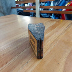 The nameplate is made of thick brown wood.  it is used as a table number sign in a restaurant.  photo taken indoors in the city of gorontalo 14 august 2022