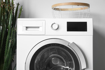 White washing machine near light wall in laundry room, closeup