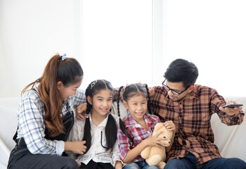 Happy Asian  family sitting watching TV in their home