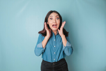 Portrait of young Asian woman isolated by blue background feeling frustrated with helpless face...