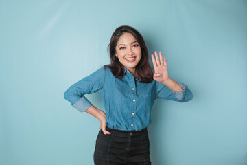 Excited Asian woman wearing a blue shirt giving number 12345 by hand gesture