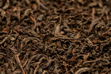 Large-leaved black tea in bulk on the table. Close-up of the surface texture