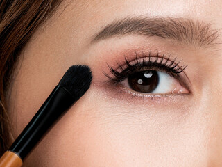 Closeup ardent young woman with healthy fair skin applying her eyeshadow with brush. Female model with fashion makeup. Beauty and makeup concept. - obrazy, fototapety, plakaty