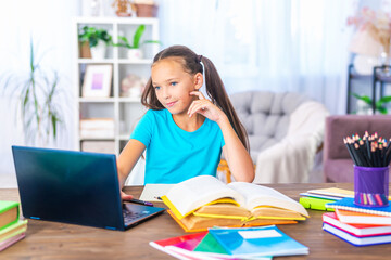 cheerful Caucasian girl uses a laptop to make video calls with her teacher. the child enjoys learning remotely. schoolgirl is happy to receive knowledge. E-Education Distance Learning, Home Schooling.