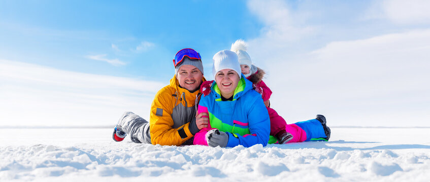 Happy family with a small child on the background of a winter landscape. Parents with their kid have fun together in the snow on a frosty day.