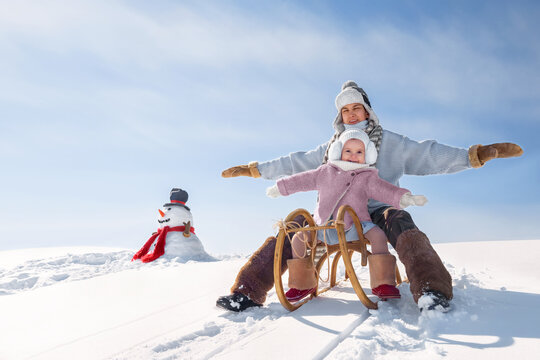 Children are sledding down the hill. Happy boy and girl in rustic style have fun on winter holidays outdoors.