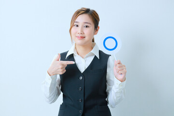 	左手に○プレートを持ち指さす笑顔のOL