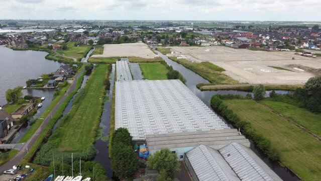Drone, aerial view of greenhouses with a new building site and European town in the background.