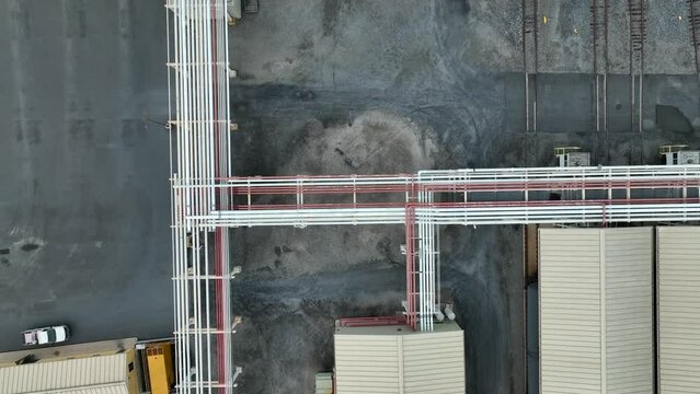 Oil and gas pipeline connects fuel storage tanks at terminal. Rising aerial reveal.