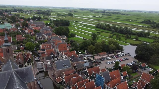 A drone flys over a small European farm village panning around the old church, canals and tall, narrow houses