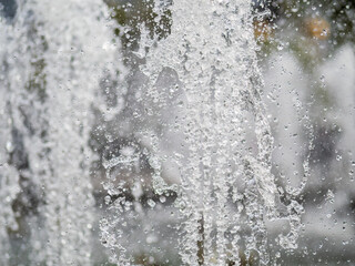 Splashes of water on dark background. Water sprays in sunny day close-up.