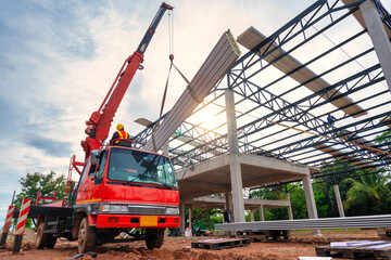 Crane driver is working on the mobile crane and lifting the roof or the PU foam roof sheet at the...