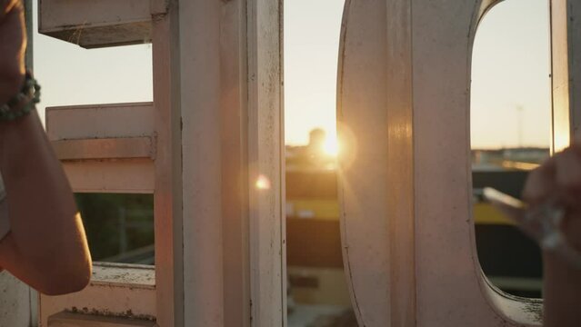 A man and a Woman cheers with a cold Drink during sunset on a rooftop during summer