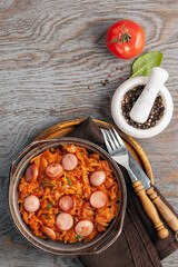 Cabbage stew with grilled sausage in tomato sauce - traditional dish of German, Polish or Russian cuisine Bigos. Top view