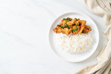 stir-fried fried fish with basil and chili in thai style topped on rice
