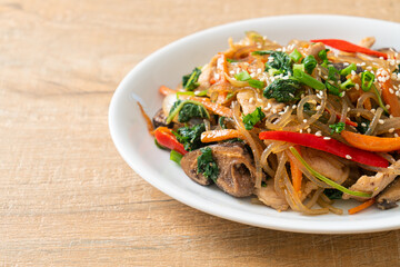 japchae or stir-fried Korean vermicelli noodles with vegetables and pork topped with white sesame