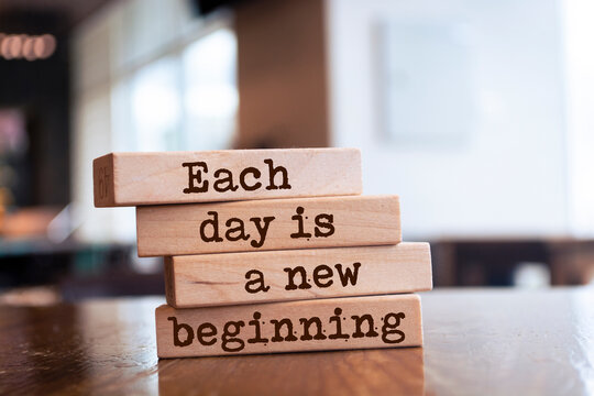 Wooden blocks with words 'Each day is a new beginning'.