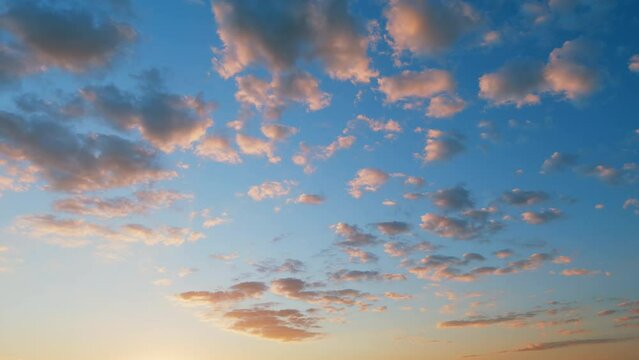 Orange to gold fluffy clouds rolling against vibrant blue sunset sky. Time lapse.