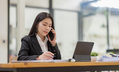 Fototapeta premium Business Asian woman talking on the phone and working with laptop calculator document on an office desk, planning analyzing the financial report, business plan investment, finance analysis concept.