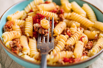 Bolognese pasta in blue plate on bright background. Traditional Italian dish