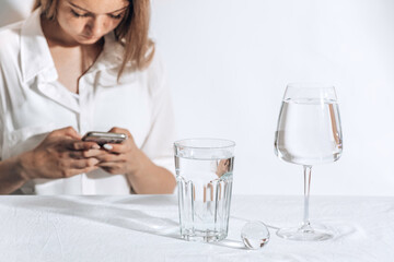 Casual style young beautiful caucasian woman texting on a smartphone. water glasses. Female model
