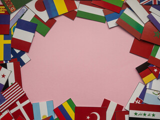 Pink background with many flags and copy space. Small flags of different countries on pink backdrop...