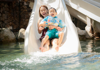 Asian boy and he mother play on the  slider water - 523459660